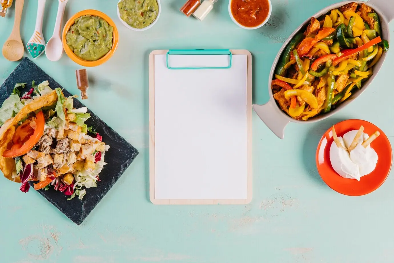 Klemmbrett und mexikanische Speisen vor blauem Hintergrund.